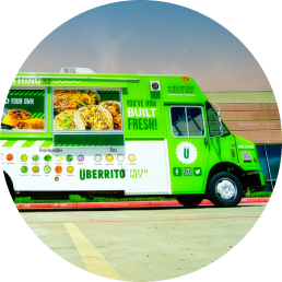 A green Uberrito Mexican food truck franchise is parked in front of a building.