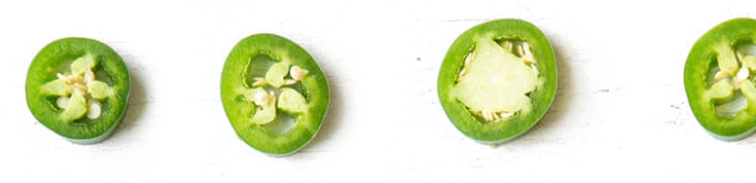 Four slices of green peppers in a row.