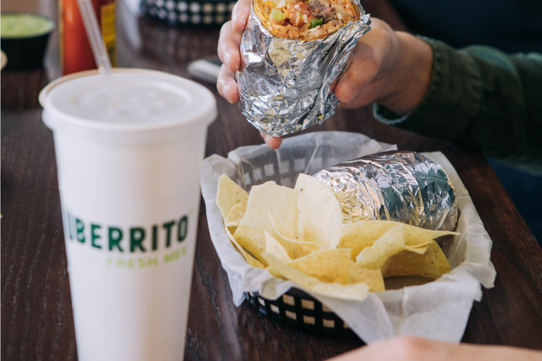 A person enjoying a delicious burrito at an Uberrito Mexican restaurant franchise.