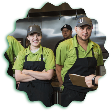 A group of people in green aprons standing next to each other at an Uberrito Mexican restaurant franchise.